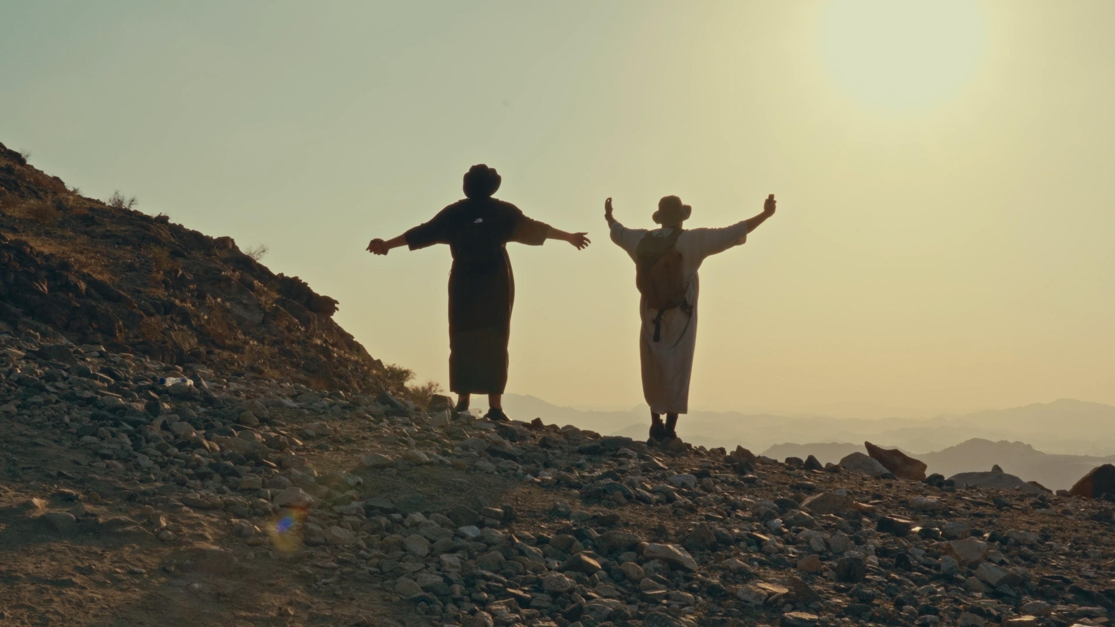 Travelers on the Hijra journey path with arms outstretched