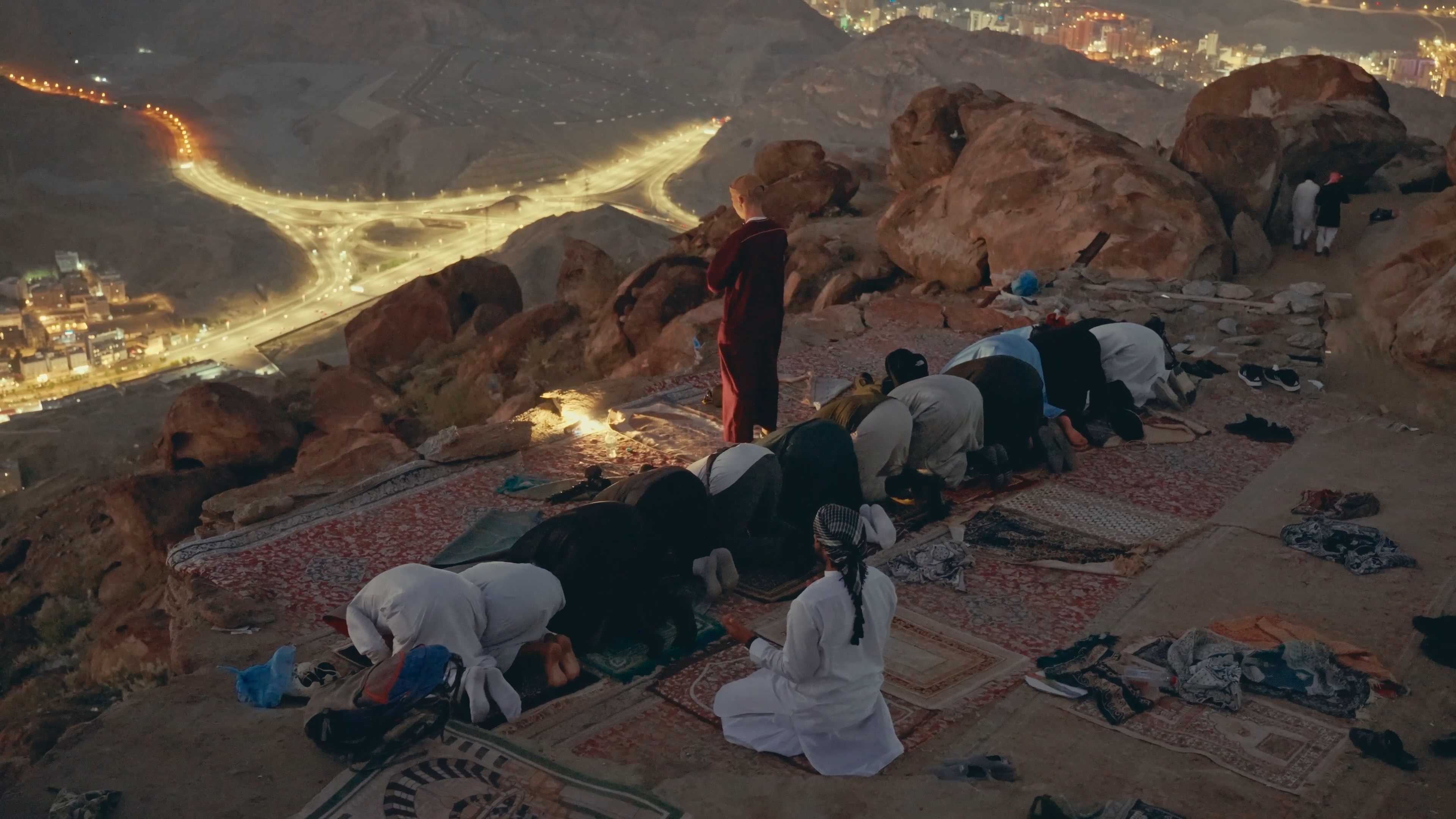 Group prayer on mountain overlooking city lights